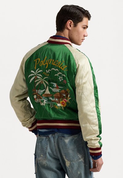 Vadderad bomberjacka med gröna och krämfärgade paneler, som har en broderad tropisk scen och flerfärgade randade kragar och ärmar.