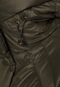 Tmavě olivově zelená prošívaná bunda s lesklým povrchem, prošívanou texturou, stažením pomocí šňůrky a bronzovými detaily kovových komponentů.