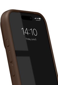 Smartphone med brunt skyddsfodral som visar tiden 14:10 och datumet fredag 6 juni på svart låsskärm med 5G-signal och batteriikoner.