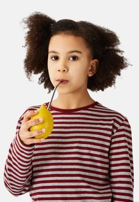 Child with curly hair wearing a red and gray striped shirt holds a yellow lemon with a stainless steel straw inserted.