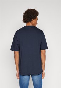 Marineblauwe katoenen t-shirt met korte mouwen en een ronde halslijn, met een ontspannen pasvorm en een zachte textuur op de achterkant.