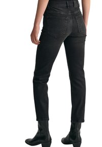 Svarta denimjeans med en figursydd design, medelhög midja och två bakfickor. Matchat med svarta läderstövlar som går upp till anklarna.