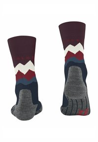 Un paio di calzini Falke con motivo montano in bordeaux, bianco, rosso, blu e grigio, che mostrano suole e talloni con imbottitura rinforzata.