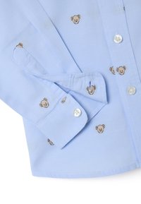 Lichtblauwe overhemdd met kleine geborduurde berenhoofden, met een enkele knoopmanchet en een gladde stoftextuur.