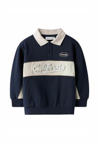 Felpa blu navy con una fascia orizzontale crema e ricamo testurizzato con la scritta "California". Presenta un colletto polo e polsini a costine.