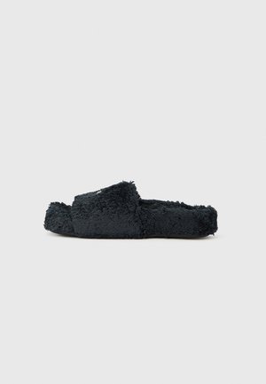 Mustad karvased lahtised varbavahe sussid laia rihmaga ja lameda tallaga, nähtud küljelt tavalise tausta peal.