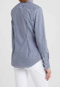 Marinblå och vit rutiga skjorta med långa ärmar, knäppningar vid ärmsluten, skräddarsydd passform och rundad nederkant, med en ryggstycke och subtil textur.