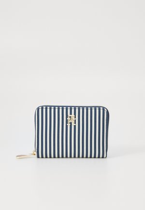 Tõmblukkuga rahakott, millel on tumesinine ja valge triibuline disain, kuldne riistvara ja silmapaistev logo esiküljel. Kompaktne ja ristkülikukujuline disain.