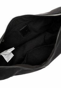 Interno di borsa in pelle nera con chiusura a zip, caratterizzato da una texture liscia e una piccola etichetta. Fodera in tessuto scuro con una leggera lucentezza.