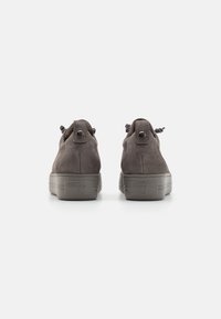 Hnědé semišové boty s texturovaným povrchem, tlustou šedou podrážkou, zaobleným tvarem a uzlovými tkaničkami vzadu.