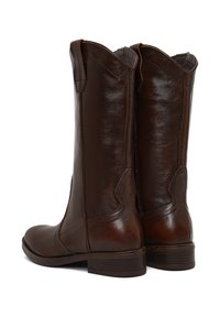 Botas de cuero marrón con una textura suave, de altura media hasta la pantorrilla, con la parte superior curvada y un tacón bajo apilado; cuenta con detalles de costura sutiles.