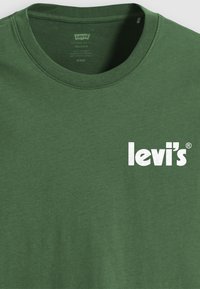Tricou din bumbac verde cu un decolteu rotund și un logo alb "Levi's" pe față. Textură fină și design cu croială lejeră.