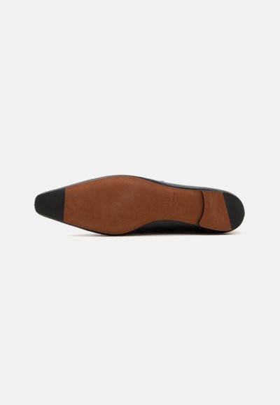 Semelle en cuir d'une chaussure formelle noire avec embouts noirs aux orteils et au talon, posée sur un fond blanc uni.
