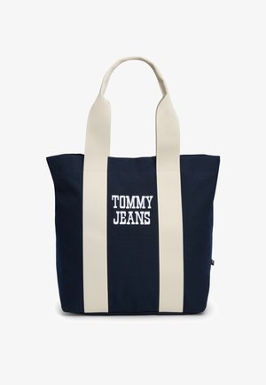 Granatowa torba na ramię z szerokimi kremowymi uchwytami i wyszywanym logo "TOMMY JEANS" na środku z przodu.