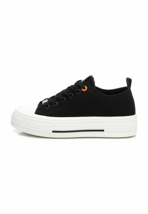 Zapatillas de lona negras con una suela de goma blanca, que presentan cordones negros, un acento en ojal naranja y una puntera texturizada.