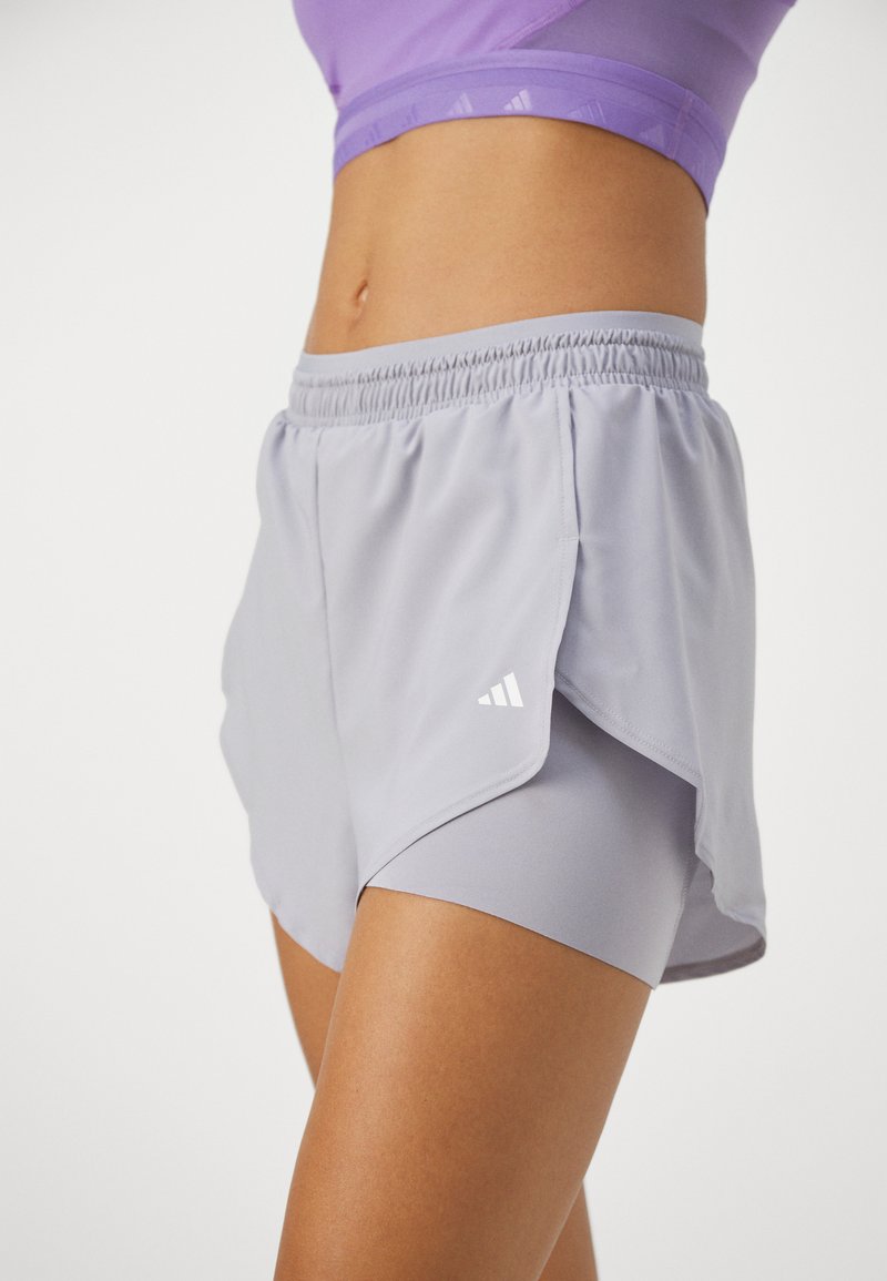 Bermudas atléticas grises con una cinturilla elástica, que presentan un diseño en capas, una textura suave y un acento de logo blanco en el lateral.