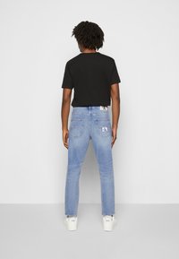 Svart t-shirt med korta ärmar i kombination med ljusblå denimjeans med bakfickor och logotag. Bärs med vita sneakers.