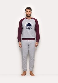 Sweat-shirt gris avec manches bordeaux, comportant le texte "NEVER STOP PLAY" et un graphique de basketball. Associé à un pantalon de survêtement gris avec des poignets élastiques.