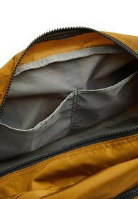 Bolsa de tela marrón con cremallera. El interior cuenta con un forro gris claro y dos bolsillos organizadores. Exterior texturizado con costuras duraderas.