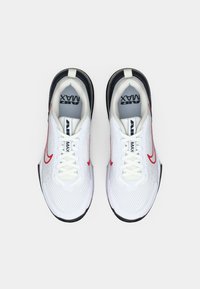 Witte sportschoenen met een bovenwerk van mesh, zwarte rubberen zool en rode accenten. Voorzien van een afgeronde neus en veters, met zichtbaar merkopdruk op de binnenzool.