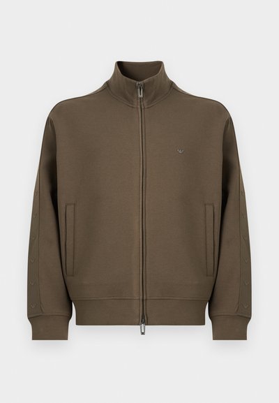 Κουκούλα με φερμουάρ μέχρι κάτω σε ελιά πράσινο χρώμα, με ψηλό γιακά, μακριά μανίκια, πλαϊνές τσέπες και μικρό λογότυπο στο στήθος και τα μανίκια.