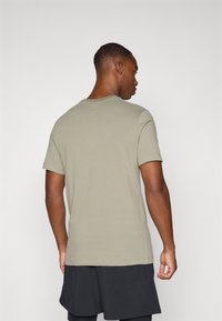 Khaki kortermet T-skjorte med rund hals, laget av mykt stoff. Bak er det et enkelt design med rett snitt og rene sømmer.