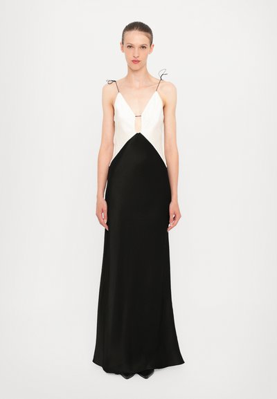 Robe sans manches noir et blanc avec un décolleté en V profond, une découpe en forme de clé et une finition satinée lisse avec de fines bretelles.