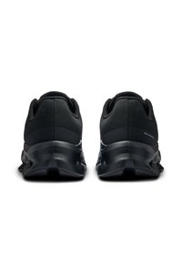 Chaussures de sport noires avec un dessus texturé, un col rembourré et une semelle en caoutchouc dotée de poches de amortissement proéminentes pour le soutien.