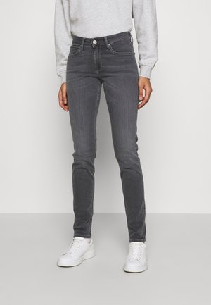 Vaqueros skinny de mezclilla gris con una cintura de tiro medio, sutiles marcas de desgaste y bolsillos frontales, combinados con zapatillas blancas y sudadera gris.