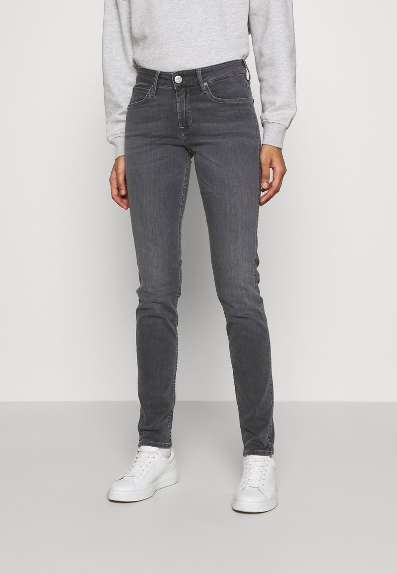 Vaqueros skinny de mezclilla gris con una cintura de tiro medio, sutiles marcas de desgaste y bolsillos frontales, combinados con zapatillas blancas y sudadera gris.