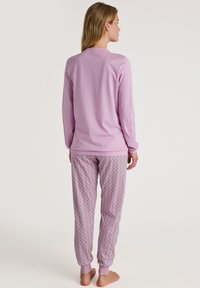 Lange mouw lavendelkleurig top met geribbelde kraag, gecombineerd met lavendelkleurige pyjamabroek met een patroon van kleine bloemen en elastische boorden.