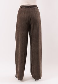 Pantaloni marroni a gamba larga realizzati in tessuto strutturato, con vita alta, pieghe frontali e chiusura con zip. Adatti per un abbigliamento casual o formale.