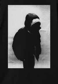 Czarna koszulka z monochromatyczną grafiką przedstawiającą postać w puchowej kurtce z kapturem, na tle teksturowanym w jasnym kolorze.