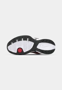 Nike sneakersål med en hvid gummimellemsål, sort ydersål, rød accent nær hælen, og struktureret slidbane for bedre greb.