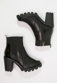 Bottines noires avec un talon épais, présentant une finition texturée, une fermeture éclair sur le côté et un tissu élastique autour de la cheville pour un ajustement parfait.