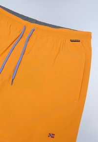 Shorts de bain orange avec une taille élastique grise, dotés de cordons de serrage bleus, de poches latérales et d'un petit drapeau norvégien brodé.