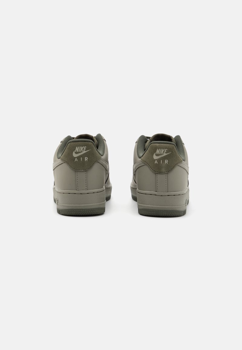 Zapatillas Nike Air gris, con un upper de cuero suave, cuello acolchado y suela texturizada. Logotipo en el talón en color contrastante.