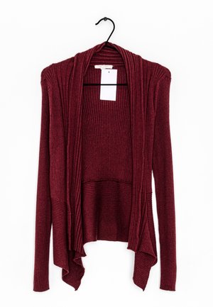 Cardigan bordeaux en tricot côtelé à manches longues, ouvert sur le devant, suspendu sur un cintre noir, avec un ourlet drapé et une étiquette blanche vierge.