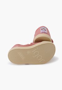 Zapatillas de lona rosa con suela de goma, que cuentan con una etiqueta de tela en el talón. La suela tiene un patrón de agarre texturizado y grabado.