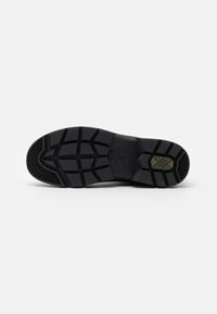 Semelle de chaussure en caoutchouc noir avec un motif de relief unique. Présente des crêtes et une surface texturée pour une traction et une stabilité optimales.