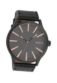 Montre analogique noire avec un cadran gris texturé, des index d'heure en or rose, et un bracelet en cuir noir. Présente un boîtier rond et un design minimaliste.