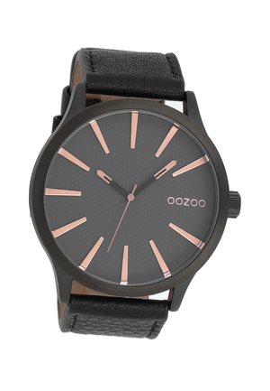 Montre analogique noire avec un cadran gris texturé, des index d'heure en or rose, et un bracelet en cuir noir. Présente un boîtier rond et un design minimaliste.