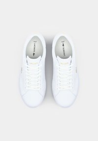 Baskets en cuir blanc avec un design à lacets, des accents perforés, un logo doré sur le côté et une languette rembourrée pour le confort.