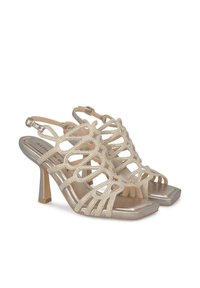 Zapatos de tacón dorados tipo slingback con diseño recortado y acentos de rhinestones, que presentan una punta cuadrada y un tacón cuadrado moderado para mayor estabilidad.