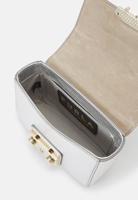 Srebrna skórzana torebka z metalicznym wykończeniem, złotym zapięciem oraz beżowym zamszowym wnętrzem z metką marki.