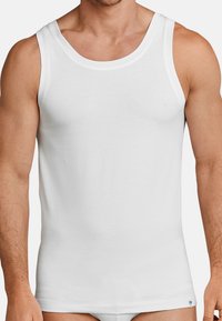 Hvid bomulds tanktop med rund halsudskæring og brede skulderstropper, der har en tætsiddende pasform og glat tekstur. Lille logo ved kanten.