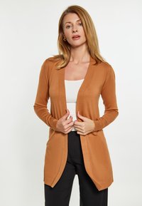 Cardigan de culoare maro deschis, fabricat dintr-un material moale, cu mâneci lungi, deschis în față, cu o croială lejeră și accente ribbed la tiv.