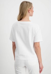 Weißes Baumwoll-T-Shirt mit Rundhalsausschnitt, kurzen Ärmeln, lockerer Passform und glatter Textur. Die Rückansicht zeigt ein einfaches Design ohne Verzierungen.