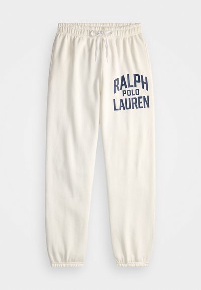 Cream-colored sweatpants made of soft cotton, featuring a large navy print of "RALPH POLO LAUREN" on the left leg and elastic cuffs.