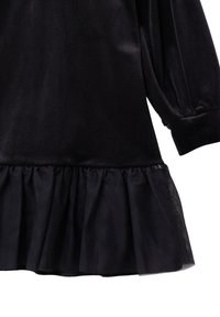 Czarna sukienka z aksamitnym górnym częścią i marszczonym tiulowym dołem. Posiada długie bufiaste rękawy i gładką fakturę na całej powierzchni.